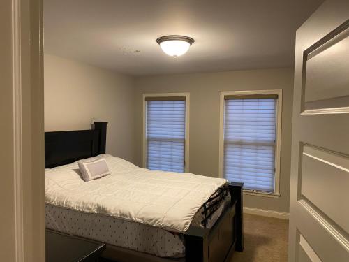 um pequeno quarto com uma cama e 2 janelas em Lakefront view private bedroom and bathroom with kitchen em McCordsville