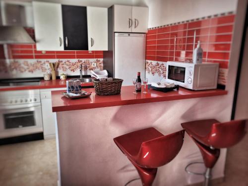 cocina con sillas rojas y encimera con microondas en Apartamento La alberca 1, en Aracena
