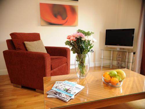 a living room with a vase of flowers and fruit on a table at PREMIER SUITES Bristol Redcliffe in Bristol