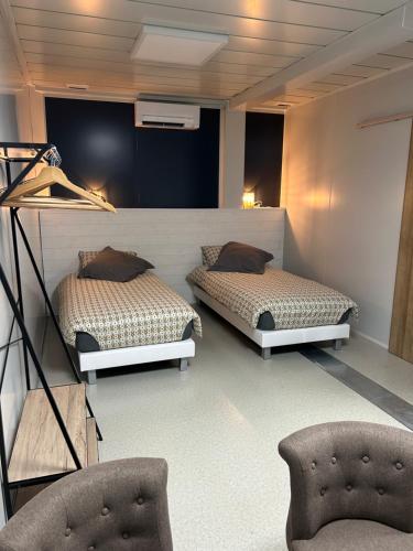 two beds in a room with two chairs at Les Chambres de Campagne in Campagne
