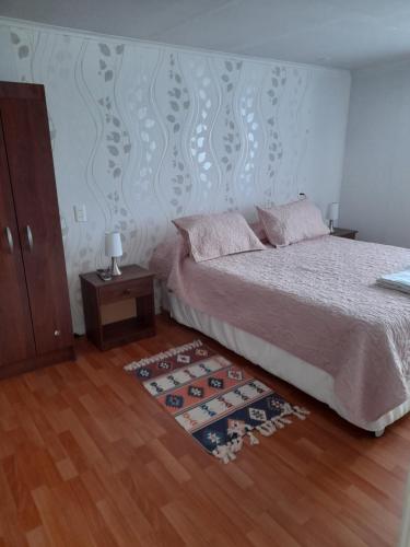 ein Schlafzimmer mit einem Bett und einem Holzboden in der Unterkunft Departamento Kran in Punta Arenas