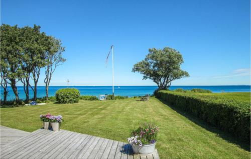 a garden with a flag pole and the ocean at 3 Bedroom Gorgeous Home In Samsø in Ballen