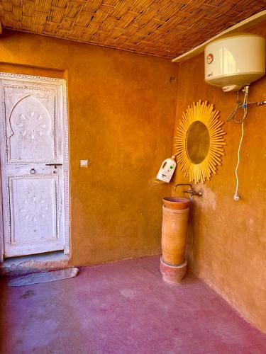 a room with a door and a mirror and a fan at Ryad lcaid in Tissint