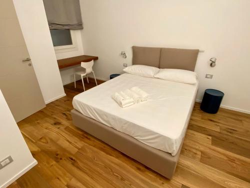 a bedroom with a bed with white sheets and a wooden floor at WeLive Trapani - luxury apartments in Trapani