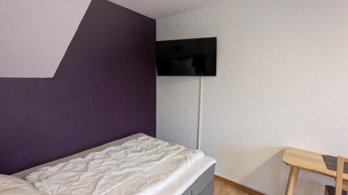 a bedroom with a bed and a purple wall at TH Exclusive in Düsseldorf