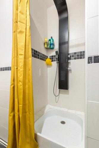 La salle de bains est pourvue d'une douche avec rideau de douche jaune. dans l'établissement 1 Apt Bohème, Parking Privé, Centre, à Cambrai