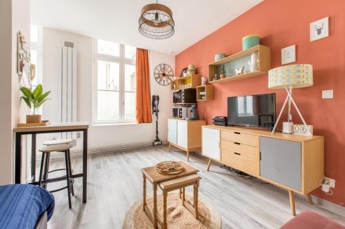 un soggiorno con pareti arancioni e TV di Apt Bohème, Parking Privé, Centre a Cambrai