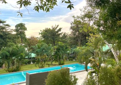 una piscina en un jardín con árboles en Siam Flora Resort Koh Lanta en Ko Lanta