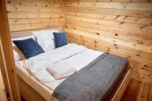 a bed in a room with a wooden wall at SŁODKA WODA DOMEK CZERWONY in Lubieszewo