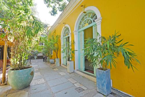 Hotel Villa Des Gouverneurs في بونديتْشيري: مبنى أصفر أمامه نباتات خزف