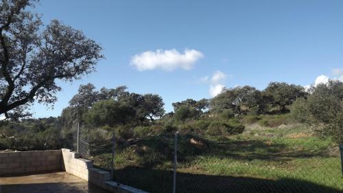 a view of a hill with trees and a fence at Villa Saudade, casa entre encinas in El Castillo de las Guardas