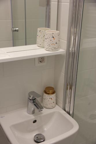 a bathroom sink with a mirror and three rolls of toiletries at Studio apartman Mirta in Varaždin