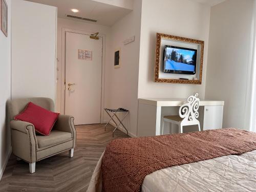 a bedroom with a bed and a chair and a television at Hotel Albatros 3 Stelle Superior in Lido di Jesolo