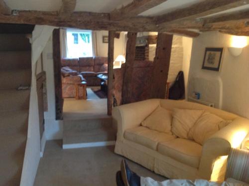 a living room with a couch and a staircase at Acacia Cottage in Halstead