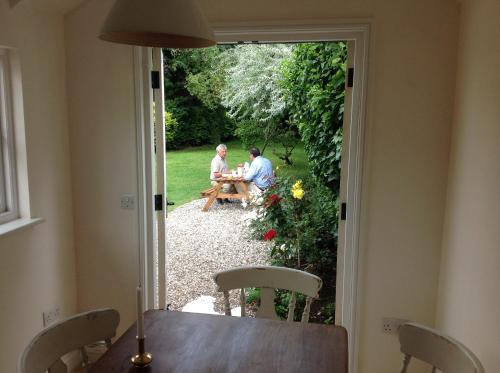 two people sitting at a table in the garden at Acacia Cottage in Halstead