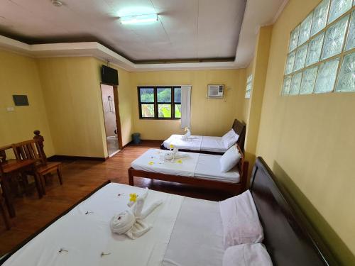 ein Hotelzimmer mit 2 Betten und einem Tisch in der Unterkunft La-Familia Guest House in Siquijor