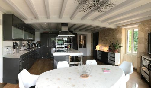 - une cuisine avec une table blanche et des chaises blanches dans l'établissement Chambres à la Ferme de Pouzatel proche Bonaguil, à Fumel