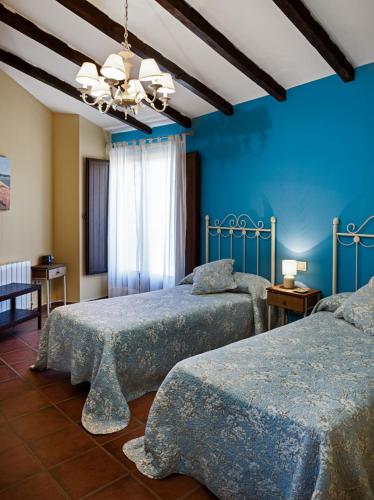 a bedroom with two beds with blue walls at Casa Rural El Caldero Sierra de Béjar in Sorihuela