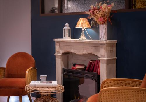a living room with a fireplace with a lamp and chairs at Hôtel Maison Lacassagne Lyon in Lyon