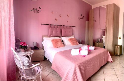 a pink bedroom with a large bed and two chairs at Butterfly House in Villaputzu