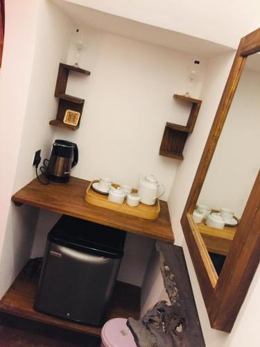 a small room with a shelf with cups and a microwave at Ella nine arch spice garden in Ella