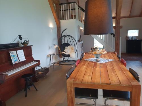a dining room with a wooden table and a piano at B&B Joostink in Vorden in Vorden