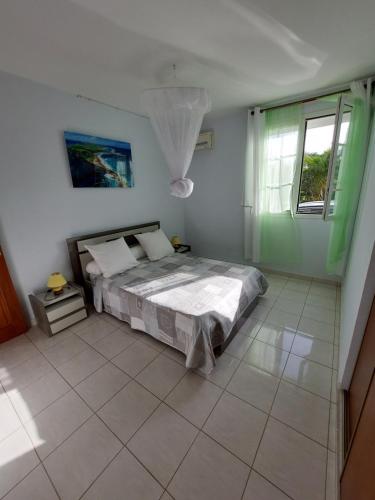 1 dormitorio con 1 cama y suelo de baldosa en Loue F2 dans maison à Saint François en Saint-François