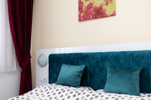 a bed with a blue headboard and two pillows at Dodona ApartHotel in Prishtina in Pristina