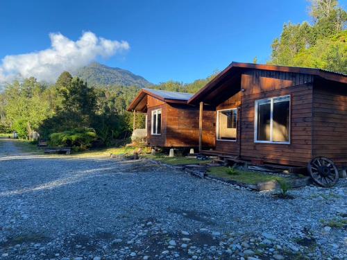 eine kleine Holzhütte mit einem Berg im Hintergrund in der Unterkunft Cabañas & Tinajas Entre Volcanes in Hornopiren