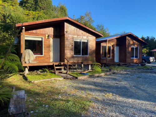 una pequeña cabaña de madera con un porche en un lote en Cabañas & Tinajas Entre Volcanes en Hornopiren