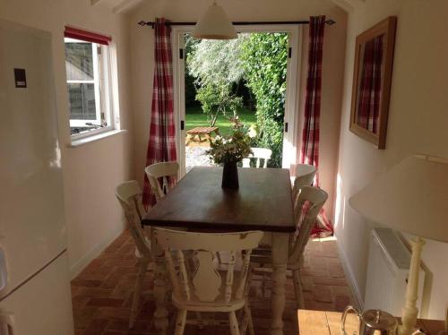 a dining room with a wooden table and chairs at Acacia Cottage in Halstead