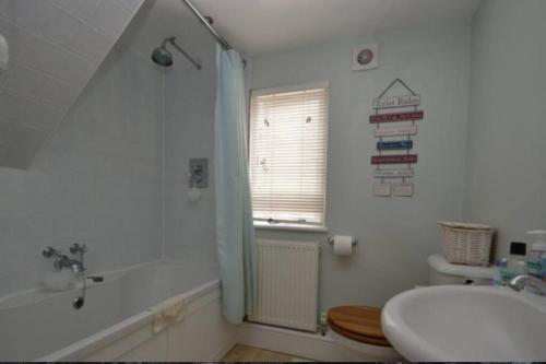 a bathroom with a tub and a toilet and a sink at Acacia Cottage in Halstead