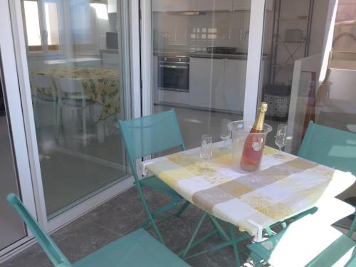 a table with a bottle of wine and two chairs at Duplex sur un fameux Grain de sable in Bonifacio