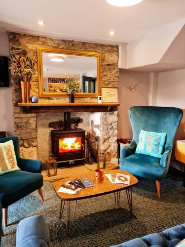 a living room with a fireplace and two chairs and a table at Furzeleigh Mill Inn in Buckfastleigh