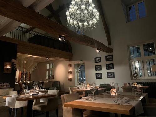 een eetkamer met tafels en stoelen en een kroonluchter bij Don Jon in Machelen