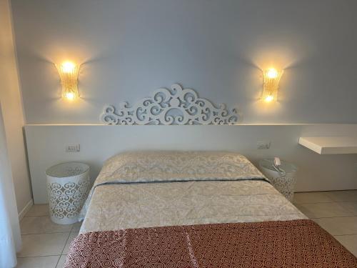a bedroom with a bed with two lights on the wall at Hotel Albatros 3 Stelle Superior in Lido di Jesolo