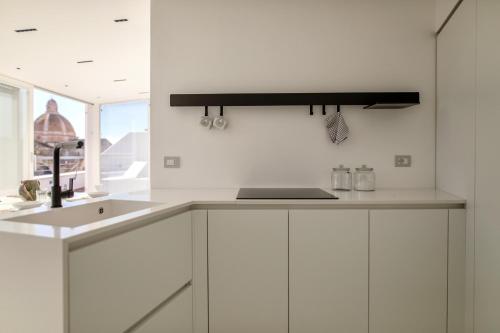 a kitchen with white cabinets and a sink at WeLive Trapani - luxury apartments in Trapani