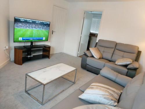 a living room with a couch and a flat screen tv at Remarkable and modern house in Rugby England in Rugby