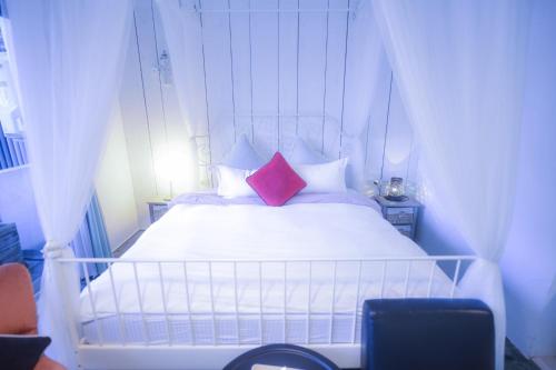 a bedroom with a white bed with two red pillows at CASA CoMoDo 自在家 in Tainan