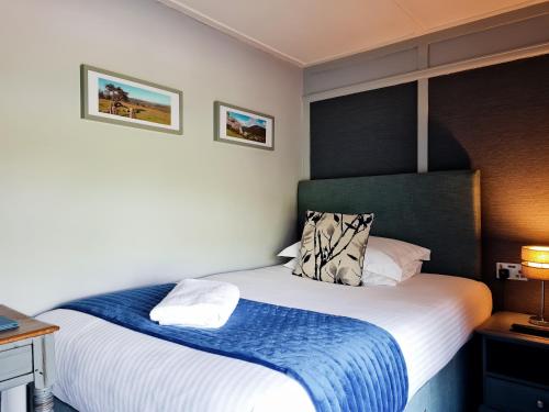 a bedroom with a large bed with a blue blanket at Furzeleigh Mill Inn in Buckfastleigh