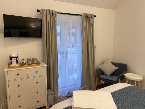 a bedroom with a bed and a dresser and a window at Rural Retreat in Devon in Plymouth