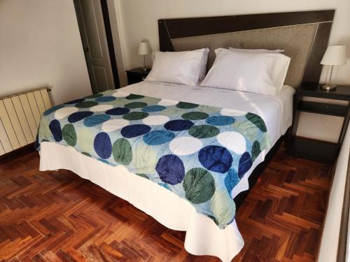 Un dormitorio con una cama con una colcha colorida. en Casa DELUXE MALBEC , Barrio Privado, con cochera doble, jardín y churrasquera en Mendoza
