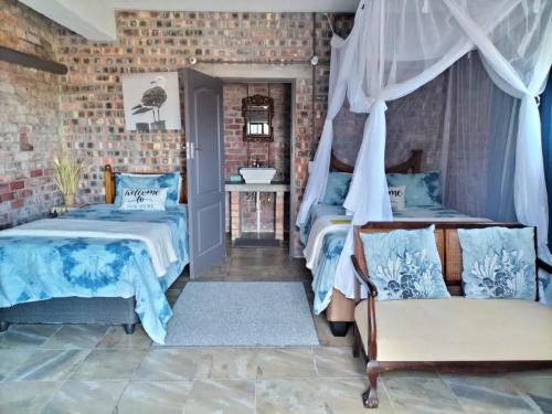 a bedroom with two beds and a brick wall at Ollava Guesthouse in Simonʼs Town