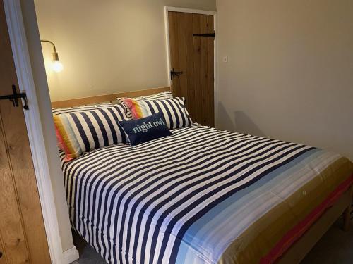 a bed with a striped blanket in a room at 4 bedroom coastal cottage with walled garden in Embleton