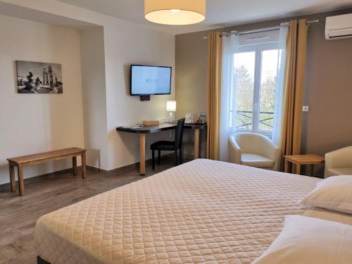 um quarto de hotel com uma cama, uma secretária e uma televisão em Chambres d'hôtes GIDY em Gidy