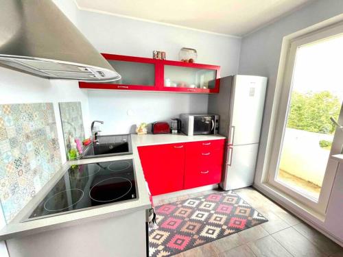 a small kitchen with red cabinets and a refrigerator at Quiet and comfortable apartment with parking for a nice stay for one,two or a couple with a child in Tallinn