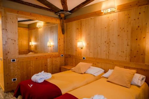 two beds in a room with wooden walls at Grand Hotel Sestriere in Sestriere