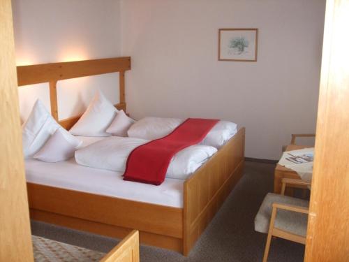 Gasthof Sölln في لام: غرفة نوم بسرير مع شراشف بيضاء وبطانية حمراء