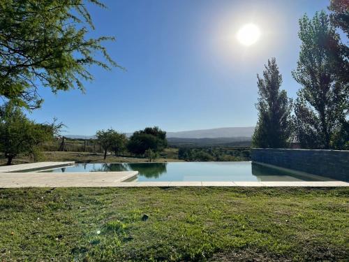 una piscina de agua con el sol en el cielo en Altos del Espinillo - Casa de Montaña in 