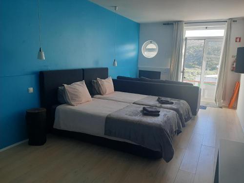 a bedroom with a large bed with a blue wall at Quartos do Seixe - Azul in Odeceixe